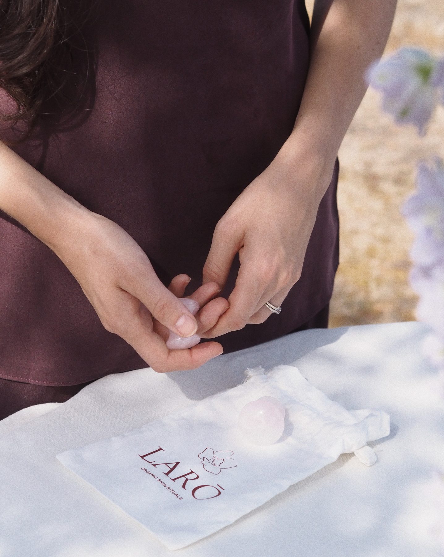 Gua sha y champiñones de cuarzo rosa sobre la bolsa de LARŌ, joyas del tocador del taller